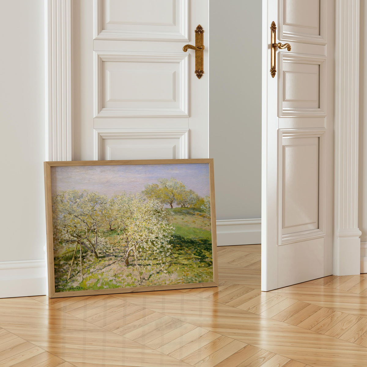 a painting of a landscape with trees and grass, displayed on a wooden floor in front of a white door.
