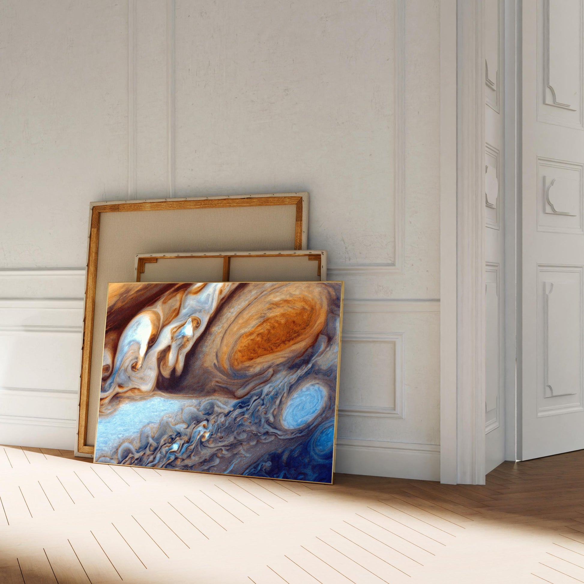 a large abstract painting with swirling patterns of blue, orange, and white colors, displayed on a white wall in a room with a wooden floor.