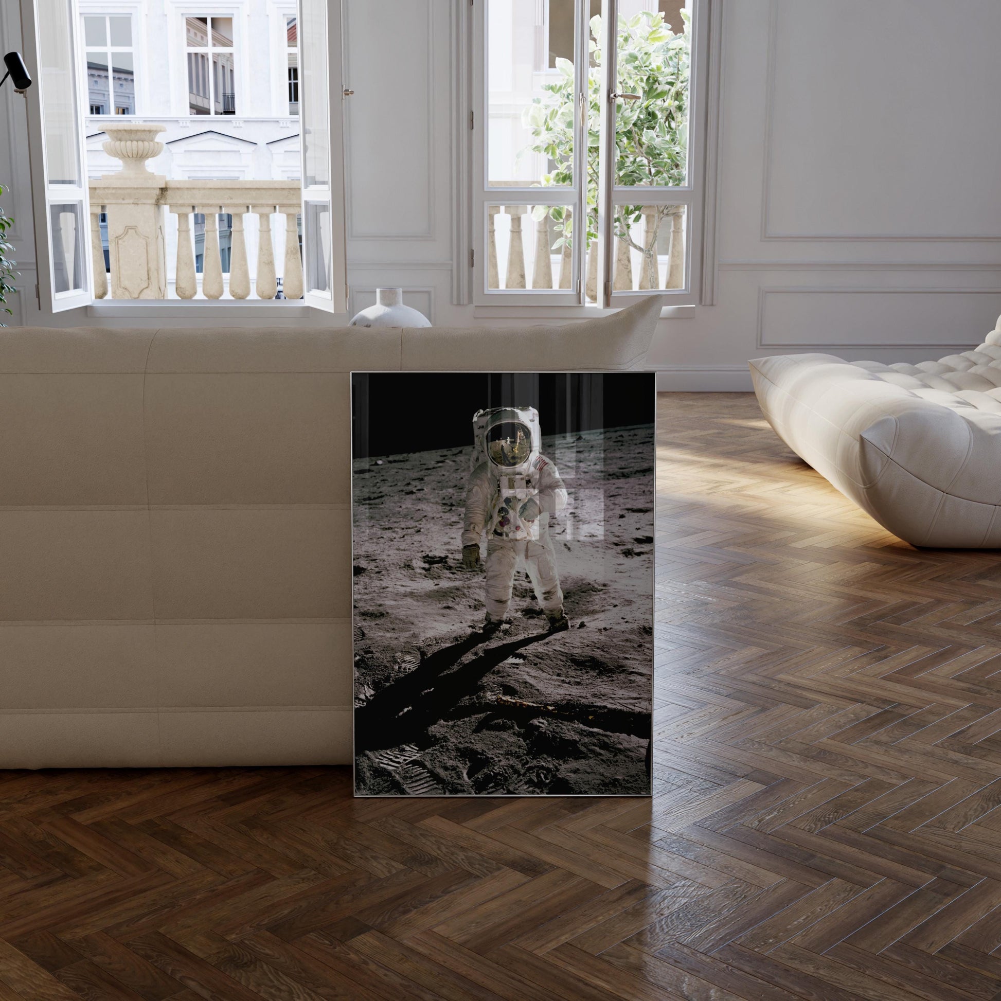 a framed photograph of an astronaut walking on the surface of the moon, with a window and a white couch visible in the background.