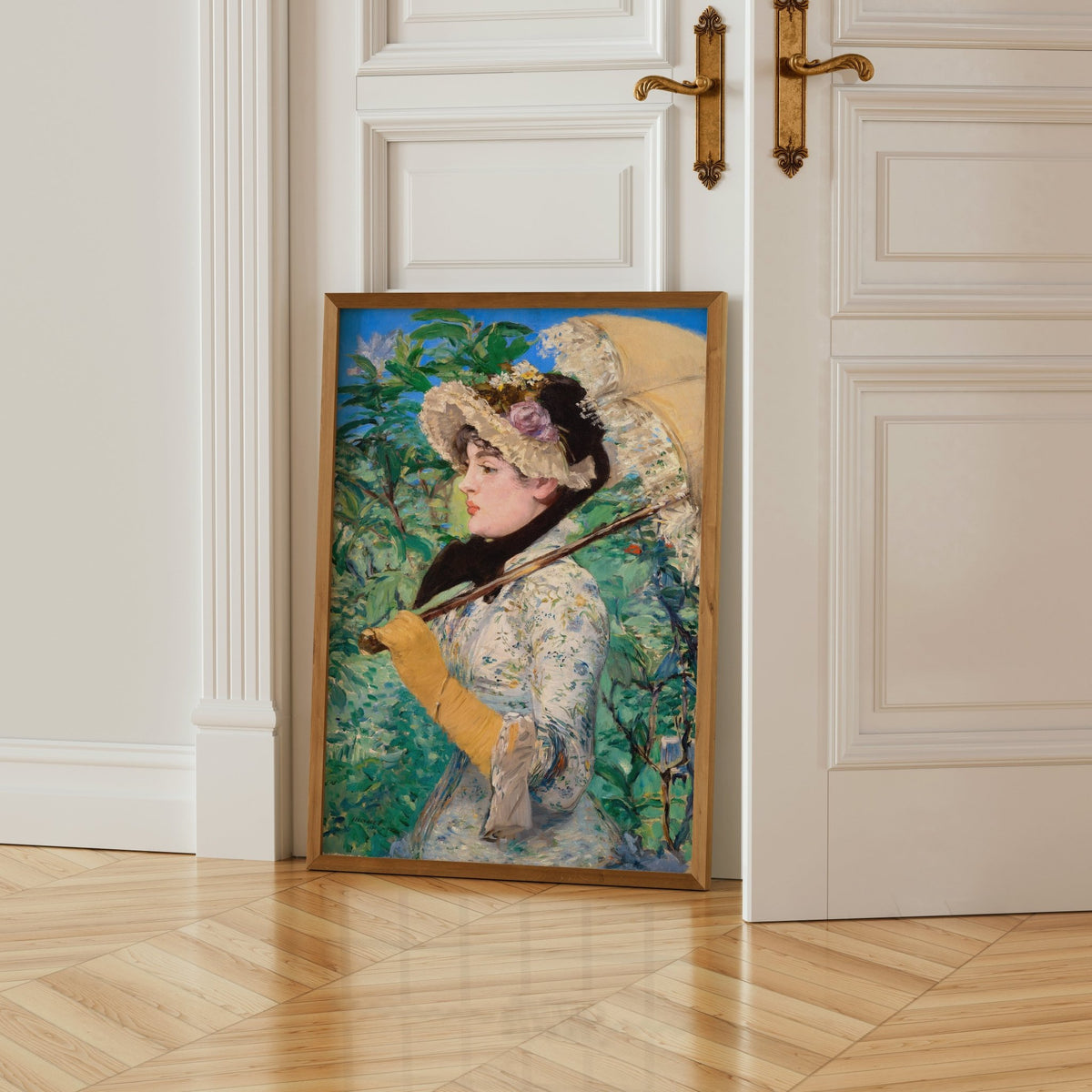 A framed painting of a woman in a white dress and hat, holding a parasol, is leaning against a white door.