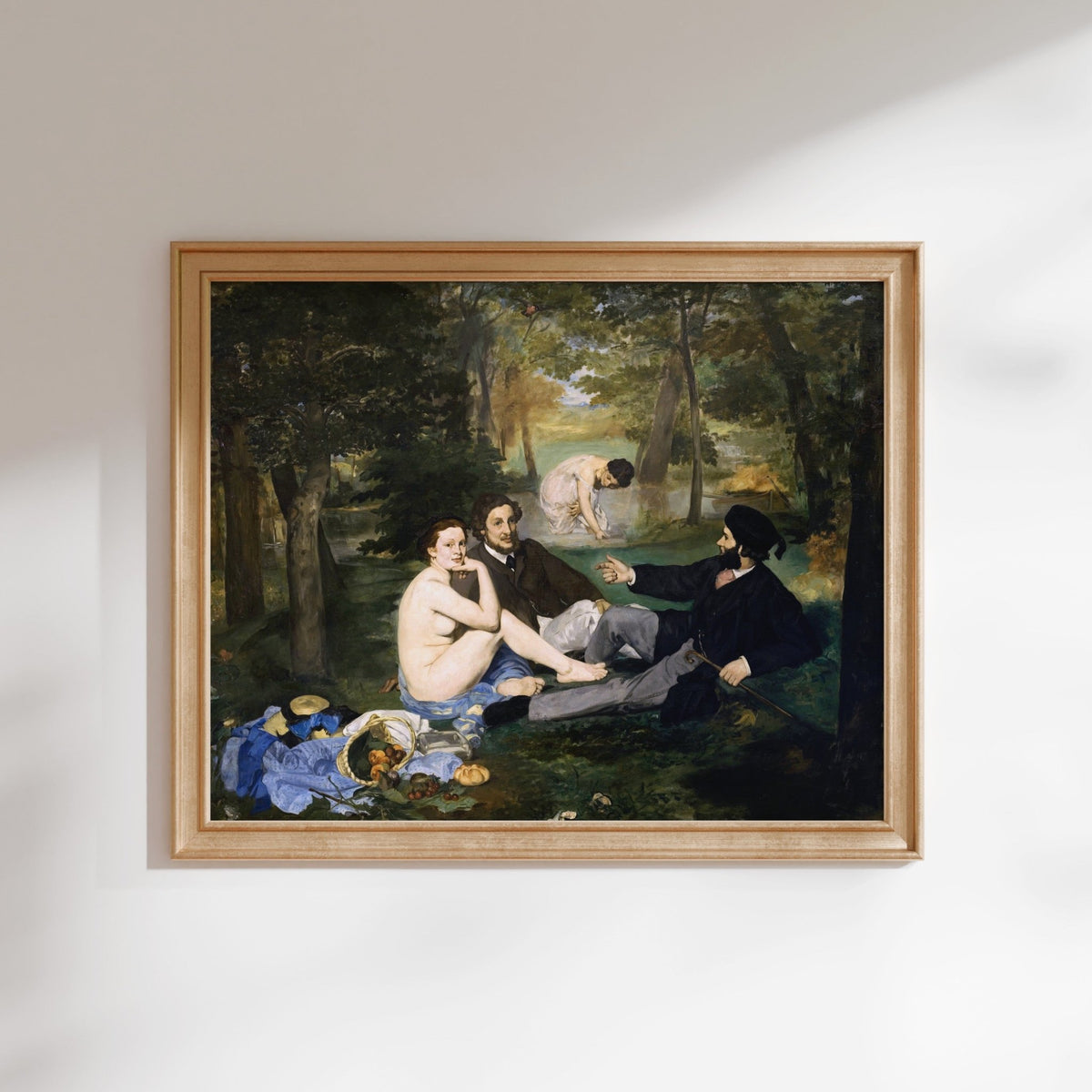 The image is a framed painting depicting a group of people sitting in a forest setting, with one person sitting naked.