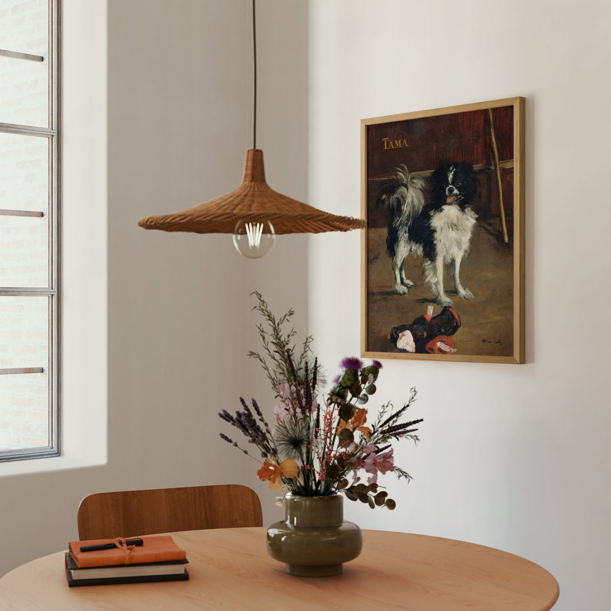 a cozy corner of a room with a wooden table, a vase of flowers, and a framed painting of a dog. A hanging light fixture is also present in the room.
