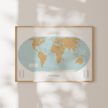 a framed world map with a light blue background and gold borders, hanging on a wall.